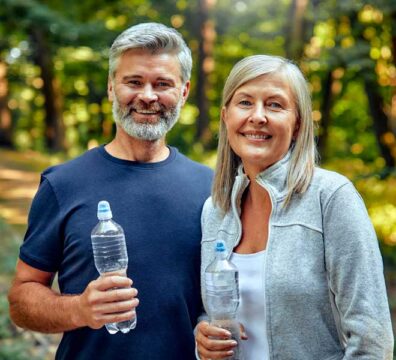 Uomo e donna sorridenti dopo l’allenamento, riflettono energia e benessere.