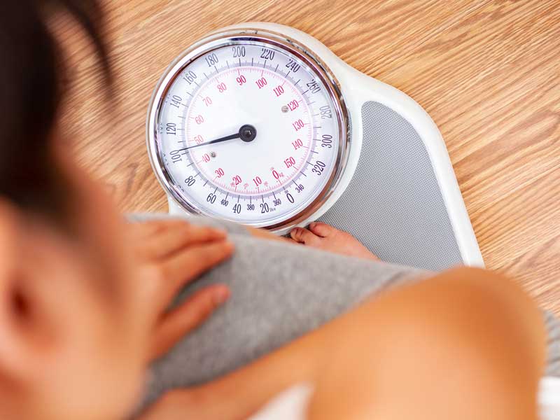 Donna in piedi sulla bilancia, mentre misura il suo peso corporeo.