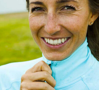 donna sorridente si allaccia la maglia sportiva