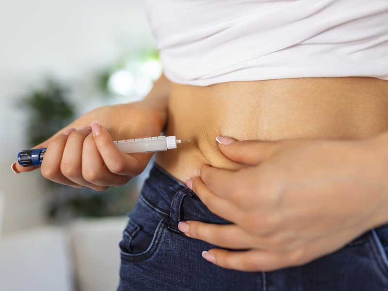 Donna si somministra una puntura di insulina sull’addome, seguendo la corretta procedura per la gestione del diabete.