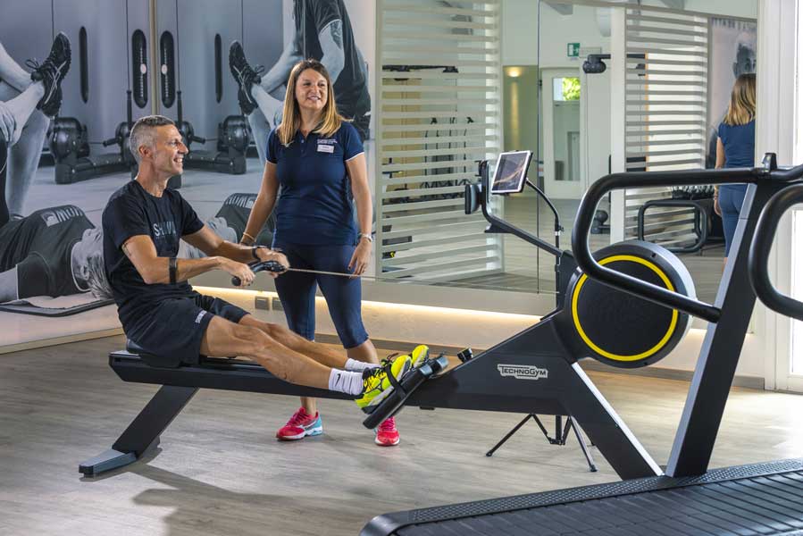 uomo in palestra sul reamatore si allena seguito da un personal trainer esperta