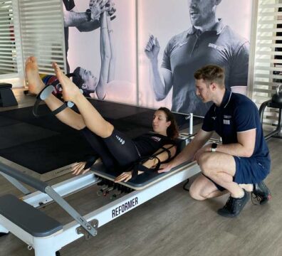 Allenamento di Pilates su Reformer in palestra, focalizzato su addome e dimagrimento, guidato da un personal trainer esperto.