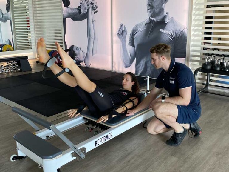 Allenamento di Pilates su Reformer in palestra, focalizzato su addome e dimagrimento, guidato da un personal trainer esperto.