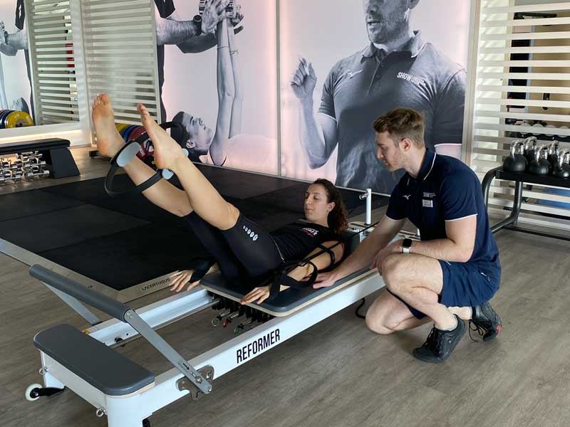 Allenamento di Pilates su Reformer in palestra, focalizzato su addome e dimagrimento, guidato da un personal trainer esperto.