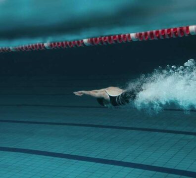 Donna immersa in piscina, appena tuffata, pronta a iniziare a nuotare.