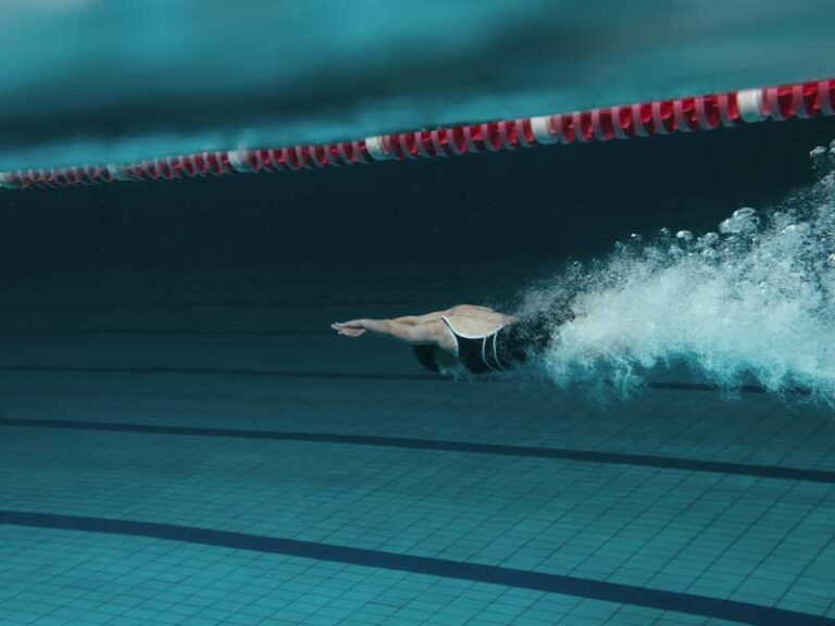 Donna immersa in piscina, appena tuffata, pronta a iniziare a nuotare.
