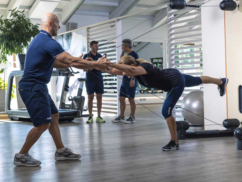 donna si allena in palestra seguita da personal trainer, esegue un esercizio per il core. è un esercizio corretto per migliorare la schiena
