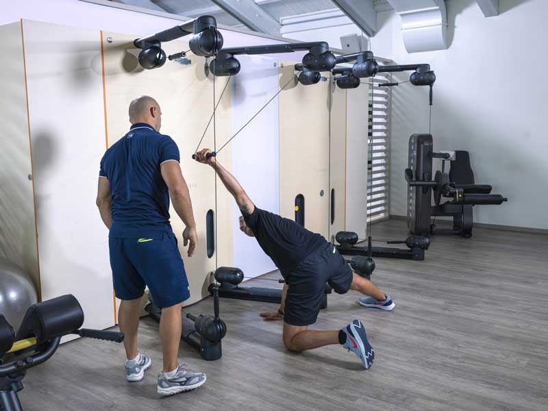 uomo in palestra con personal trainer fa esercizi efficaci per la schiena