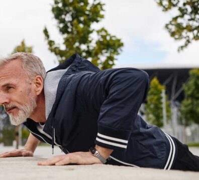 uomo si allena al parco, sta facendo un allenamento metabolico e sta eseguendo l'esercizio push-up su un muretto