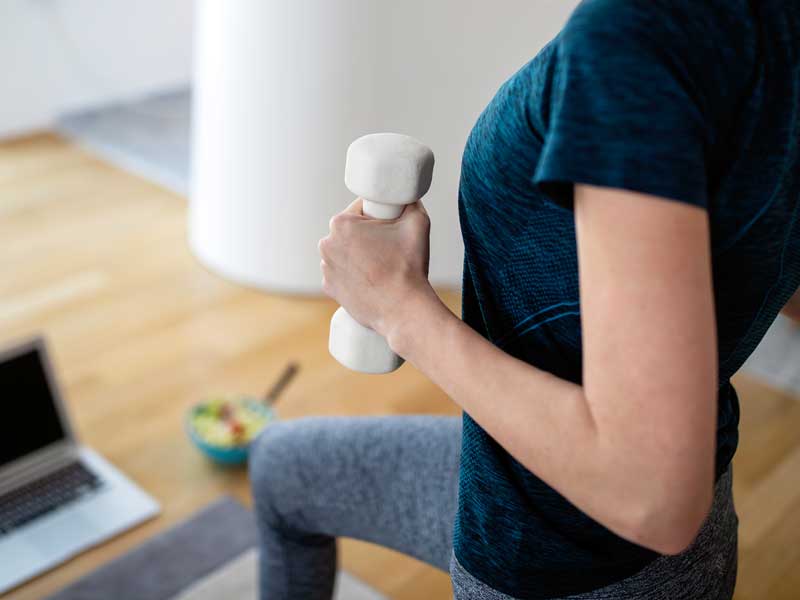 allenamento i ufficio durante la pausa pranzo. donna si allena con pesi in mano