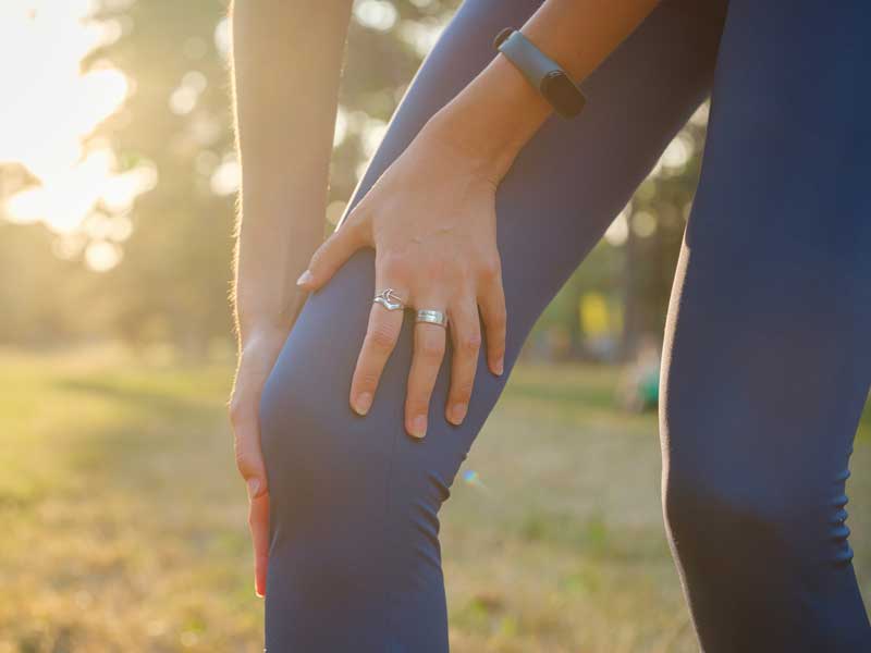 donna infortunata si tiene con le mani il ginocchio perché si è fatta male