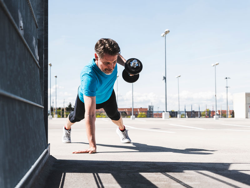 Uomo che esegue un esercizio di allenamento HIIT con manubrio per sviluppare forza e resistenza