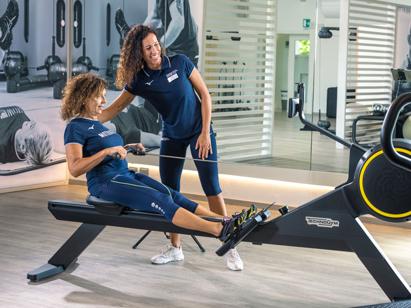 donna si allena in palestra seguita da perosonal trainer e allena la forza e fiato