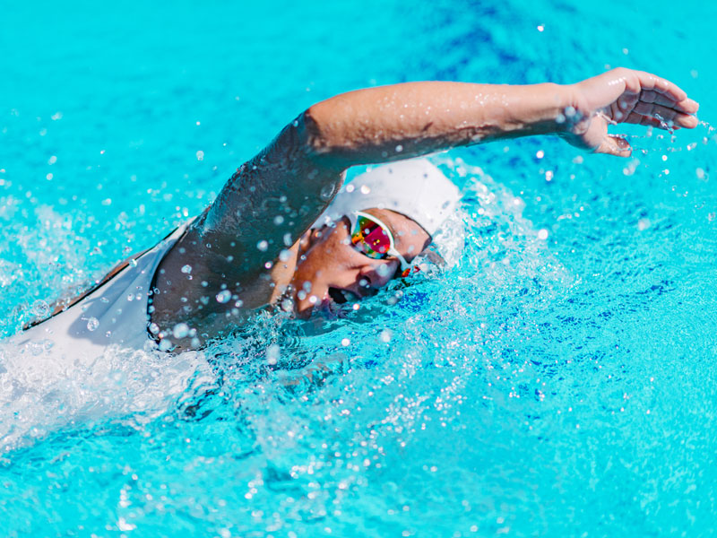 Persona nuota a stile libero durante un allenamento di nuoto per dimagrire.