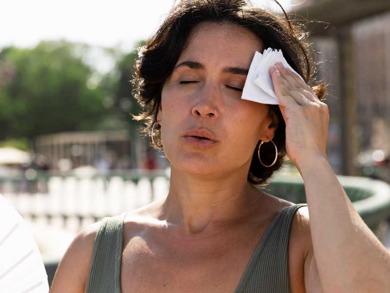 Giornata molto calda, donna si sventola con un ventaglio e si asciuga il sudore