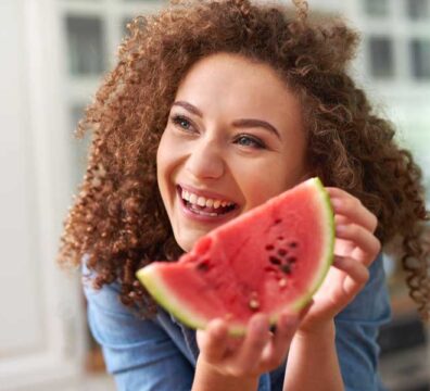 donna sorridente si prepara a mangiare uno spicchio di anguria