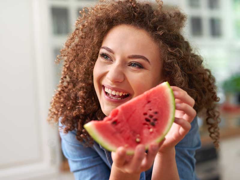 donna sorridente si prepara a mangiare uno spicchio di anguria