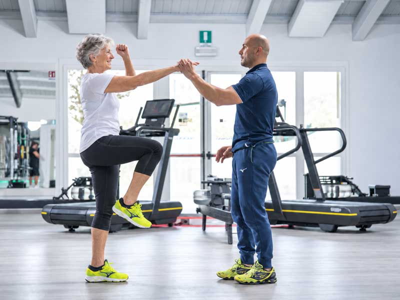 donna in palestra fa esercizi di equilibrio seguita dal suo personal trianer
