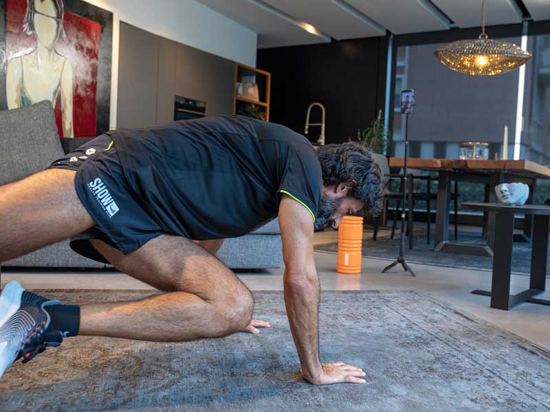 uomo di 50 anni si allena a casa in video chiamata online guidato da un personal trainer